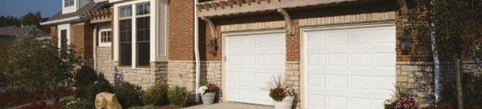 Before photo showing a Casa Grande home with two plain white garage doors and potted plants on the driveway.