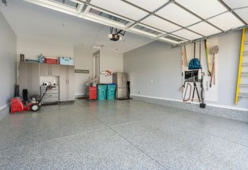 Spacious Casa Grande garage with a newly installed overhead door, organized storage cabinets, wall-mounted tools, and a clean epoxy floor.