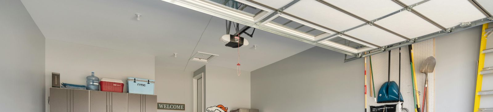 Spacious Casa Grande garage with a newly installed overhead door, organized storage cabinets, wall-mounted tools, and a clean epoxy floor.