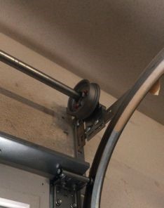 Close-up of the garage door cable drum and newly installed cable securely fastened to the bracket and track in a Coolidge home.