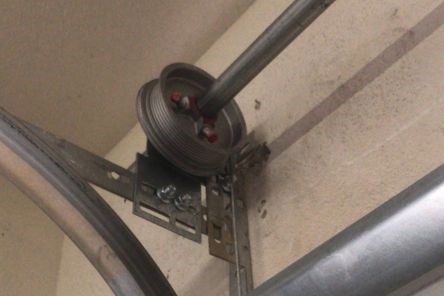 Detailed shot of the garage door cable system and hardware, highlighting the new cable installation and secure attachment in a Coolidge residential garage.