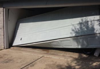 White garage door in Coolidge severely off its tracks, hanging crookedly with a visible gap at the top and bottom.