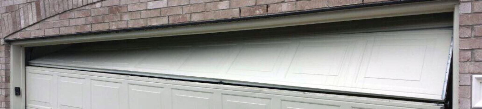 Light-colored garage door collapsed inward and off its tracks, partially blocking the driveway of a Coolidge home.