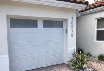 Front view of a modern Eloy home with a new double garage door featuring upper glass panels and a clean, paved driveway.