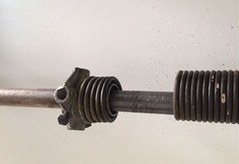 Close-up of a broken torsion spring on a Casa Grande garage door, showing visible separation and rust on the coils.